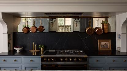 A kitchen range area with blue cabinets and a mirrored backsplash