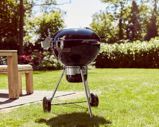 Weber Master Touch Premium charcoal BBQ on a lawn next to a patio