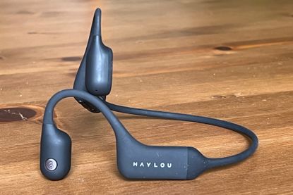 This image shows the Haylou PurFree wireless bone conducting headphones on a wooden table