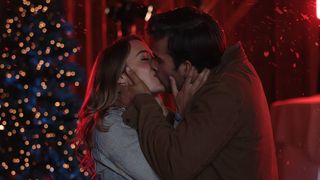 Lauren and Josh Swickard kiss by a christmas tree in a california christmas