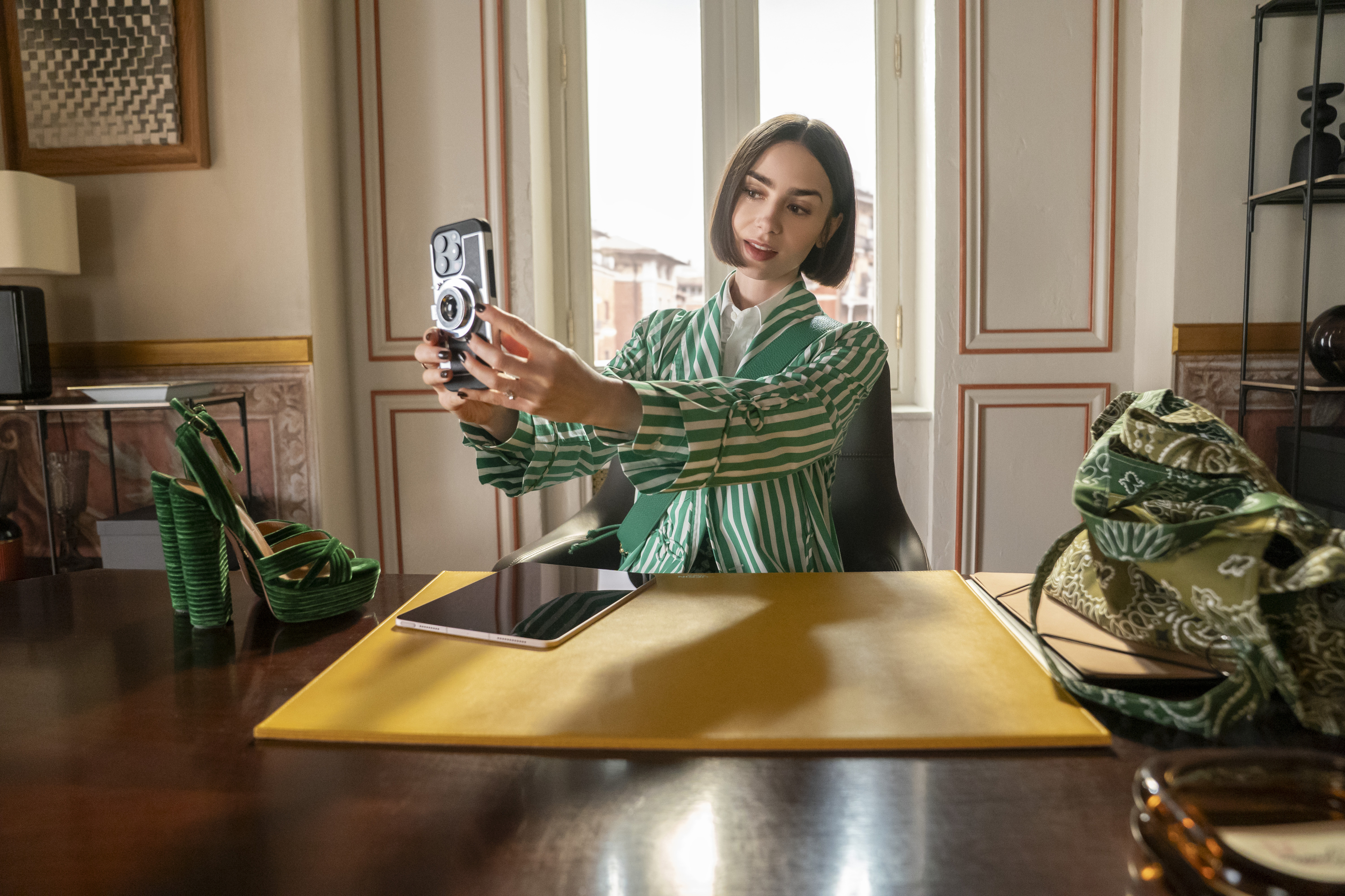lily collins as emily wearing a green striped suit and taking a selfie in emily in paris season 5