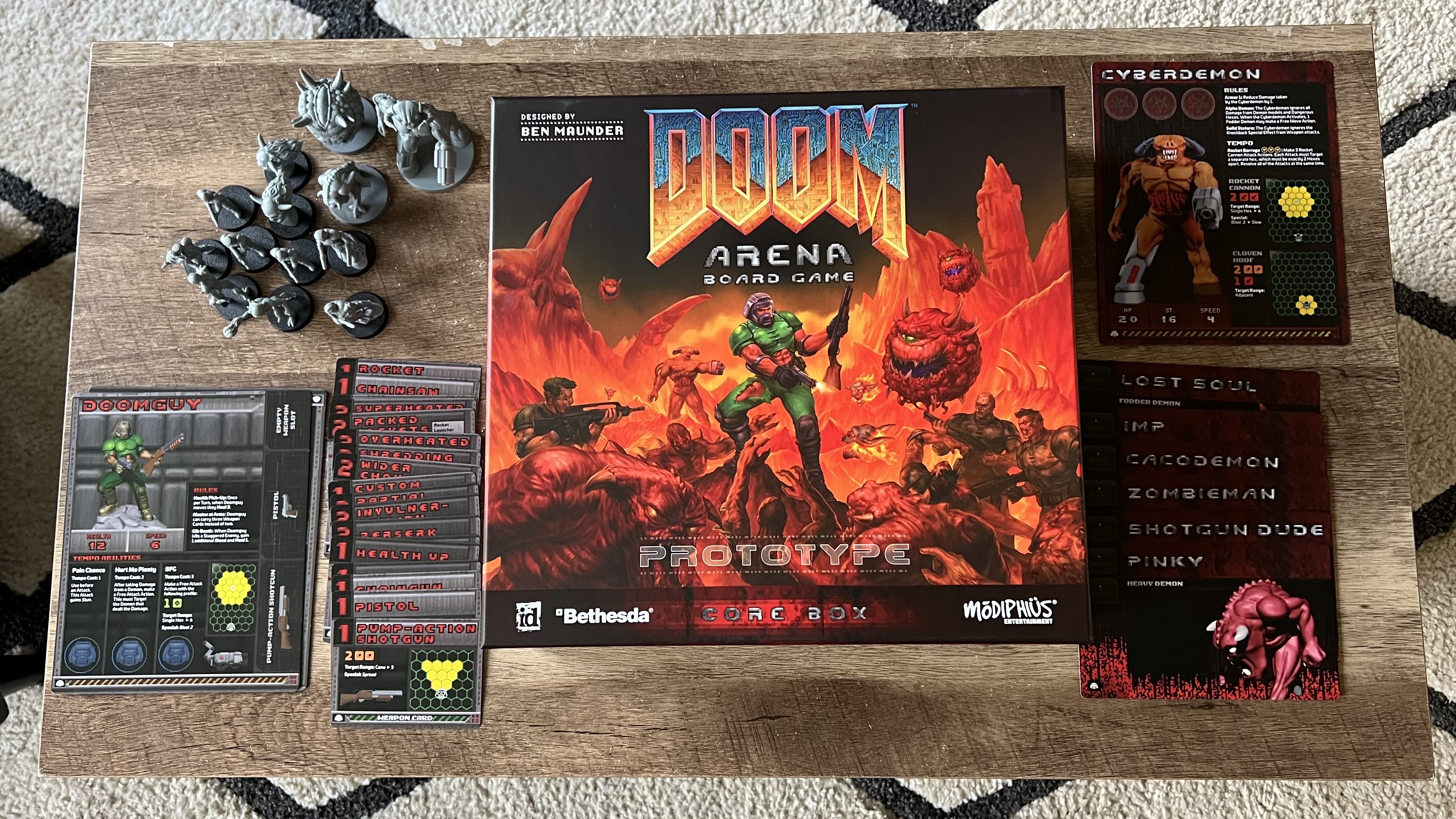Doom Arena Board Game box on a wooden table with character and upgrade cards and miniatures on either side