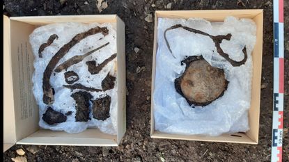 Two cardboard boxes holding metal artifacts found in the Viking Age burial, including knives, a cloak brooch and the remains of a shield.