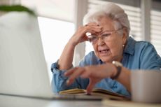 Older woman looking at computer screen with head in hand