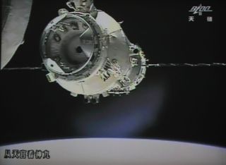 A giant screen at the Chinese space center shows Shenzhou-9 crewed vehicle approaching the Tiangong-1 space station module.
