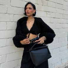 Nara Smith taking a photo outside in front of a white wall 