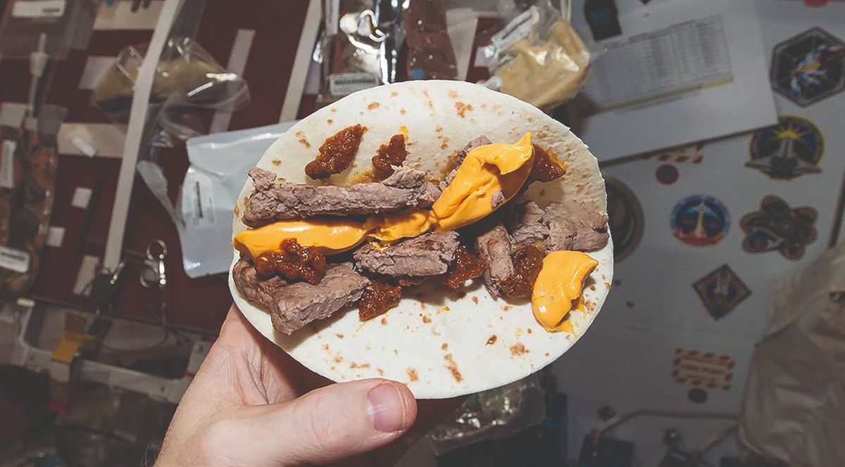 A "deconstructed" looking cheeseburger, with beef patty, cheese, tomato paste and mustard on a tortilla wrap.