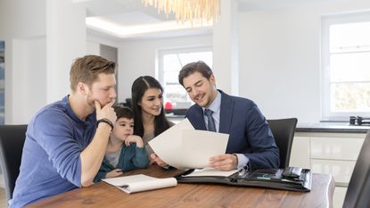 A couple and their child sit at a table with an adviser to talk about financial planning.