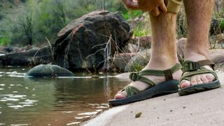 Man Wearing Sandals on a Concrete Boat Ramp Rolls Up His Khaki Pant Legs Next to the Colorado River
