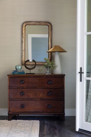 Chest of drawers in dark wood with gold mirror and white lamp