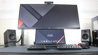 A portable monitor underneath an ultrawide monitor on a desk