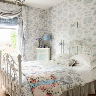 guest bedroom with bedstead toile wallpaper curtains and bedlinen