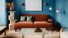 a blue living room with a rust colored sofa and decorative objects around. 