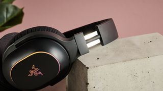 Close-up of headband adjustment on Razer Barracuda X Chroma, resting on plinth with plant and pink in background