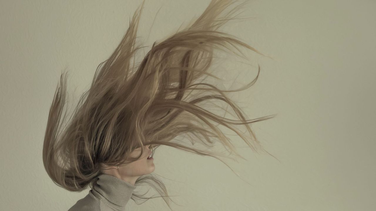 woman lifting her head up quickly with her hair up in the air - best products for dry hair