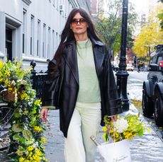 Katie Holmes in a green sweater, green pants, and black jacket