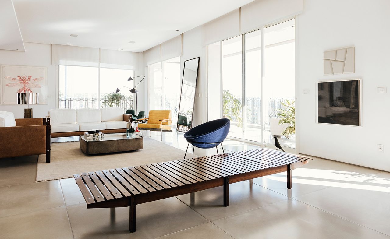 In the living space, clockwise from left, ’Millôr’ sofas by Sérgio Rodrigues; table lamp by Paolo Mendes da Rocha; Libeluis Moi Même by Rodolpho Parigi; Moi Même by Rodolpho Parigi; coffee table and ’Adriana’ armchairs (just seen) by Jorge Zalszupin; standing lamp by Serge Mouille; yellow ’Beto’ chair by Sérgio Rodrigues; mirror by B&amp;B Italia; ’Bowl’ chair by Lina Bo Bardi; ’Mucki’ bench by Sérgio Rodrigues; ’Eames House Bird’ by Charles and Ray Eames; and Branco Gelo by Marcelo Moscheta.