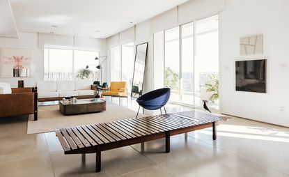 In the living space, clockwise from left, ’Millôr’ sofas by Sérgio Rodrigues; table lamp by Paolo Mendes da Rocha; Libeluis Moi Même by Rodolpho Parigi; Moi Même by Rodolpho Parigi; coffee table and ’Adriana’ armchairs (just seen) by Jorge Zalszupin; standing lamp by Serge Mouille; yellow ’Beto’ chair by Sérgio Rodrigues; mirror by B&B Italia; ’Bowl’ chair by Lina Bo Bardi; ’Mucki’ bench by Sérgio Rodrigues; ’Eames House Bird’ by Charles and Ray Eames; and Branco Gelo by Marcelo Moscheta.