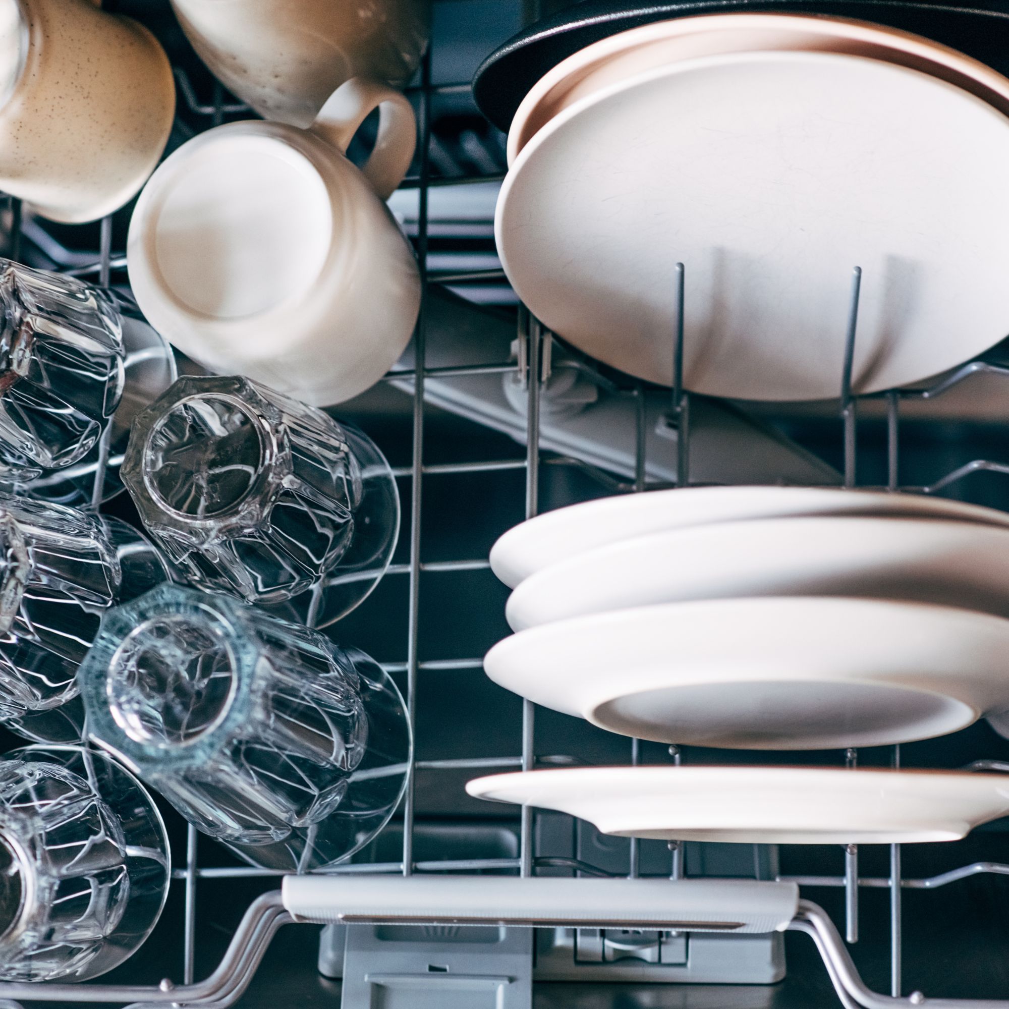Plates, glassed and mugs stacked on a shelf in a dishwasher