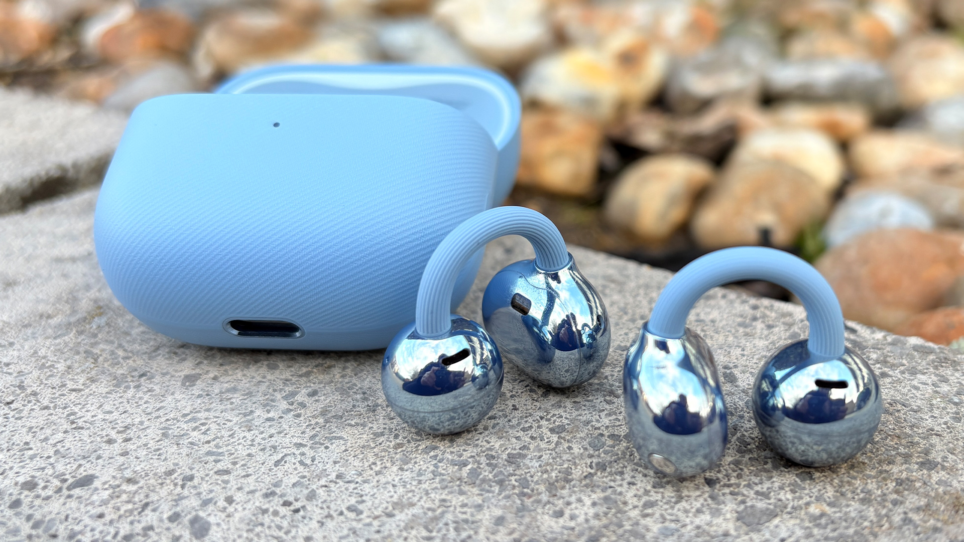 Huawei FreeClip 2 wireless earbuds on concrete next to open charging case