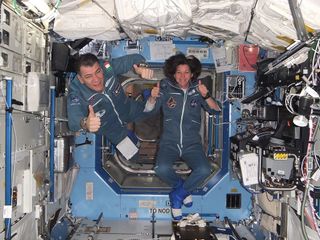 Italian astronaut Paolo Nespoli and NASA astronaut Cady Coleman give hearty thumbs up signs after reaching the International Space Station. This photo was taken on the station on Dec. 18, 2010, a day after the Soyuz TMA-20 craft carrying the astronauts ar