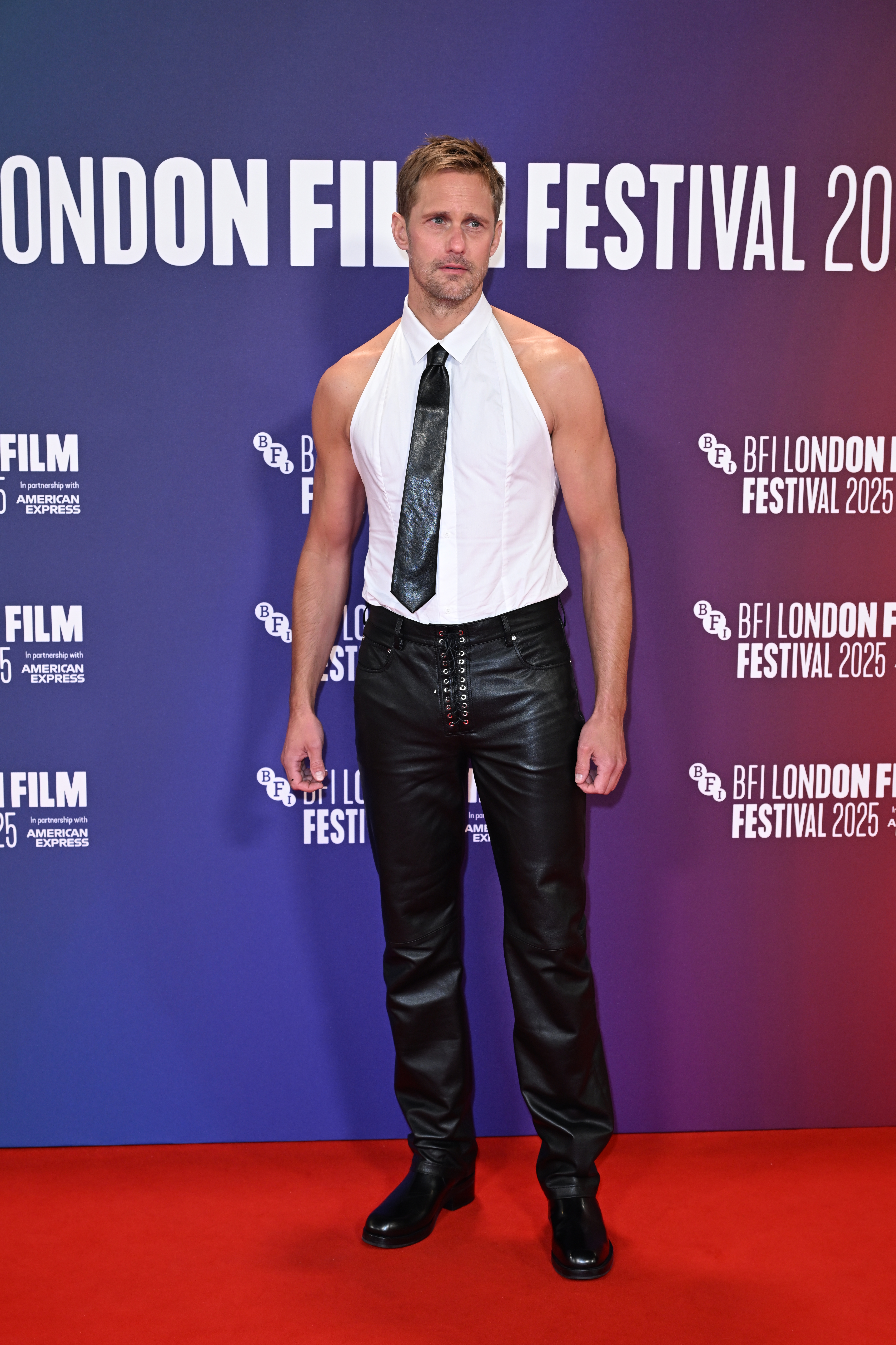 Alexander Skarsgard wears leather pants and a backless halter top on the red carpet promoting his new film, Pillion