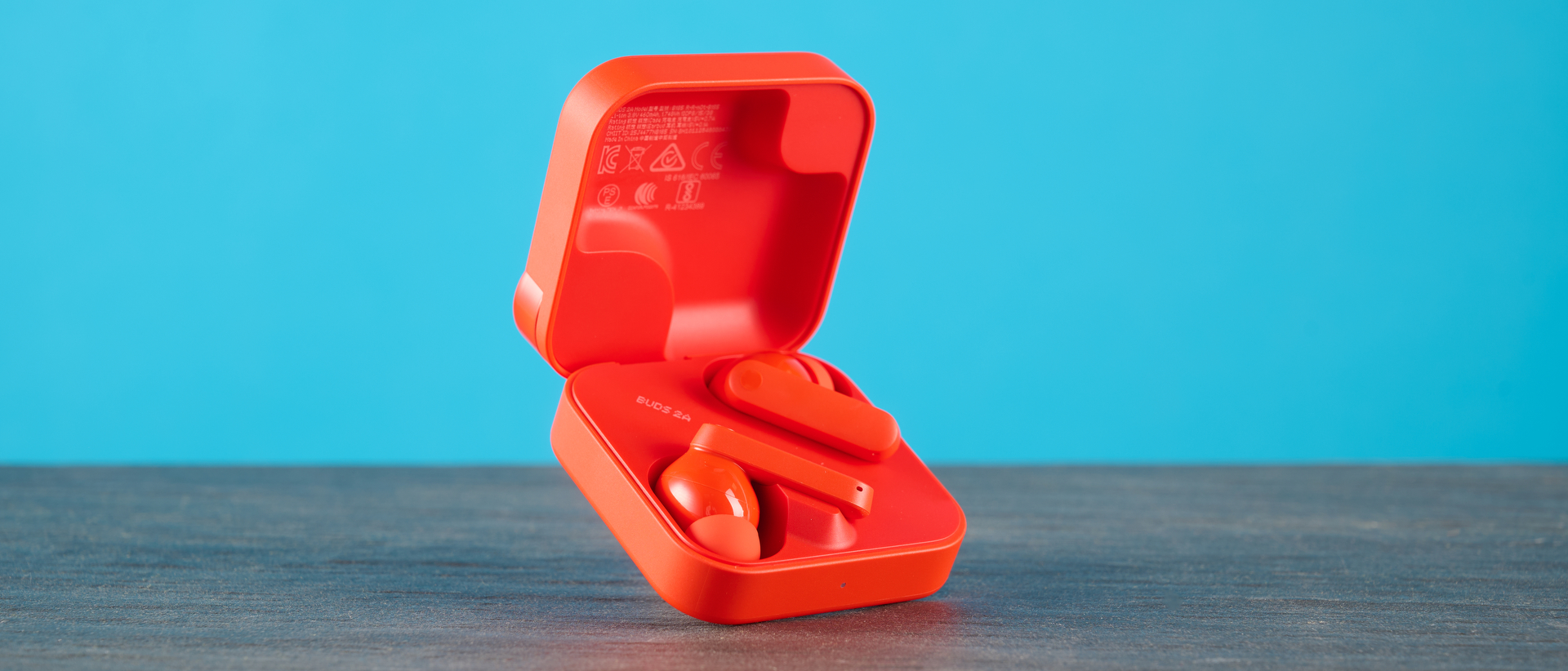 cmf buds 2a in the orange colorway photographed in front of a blue background