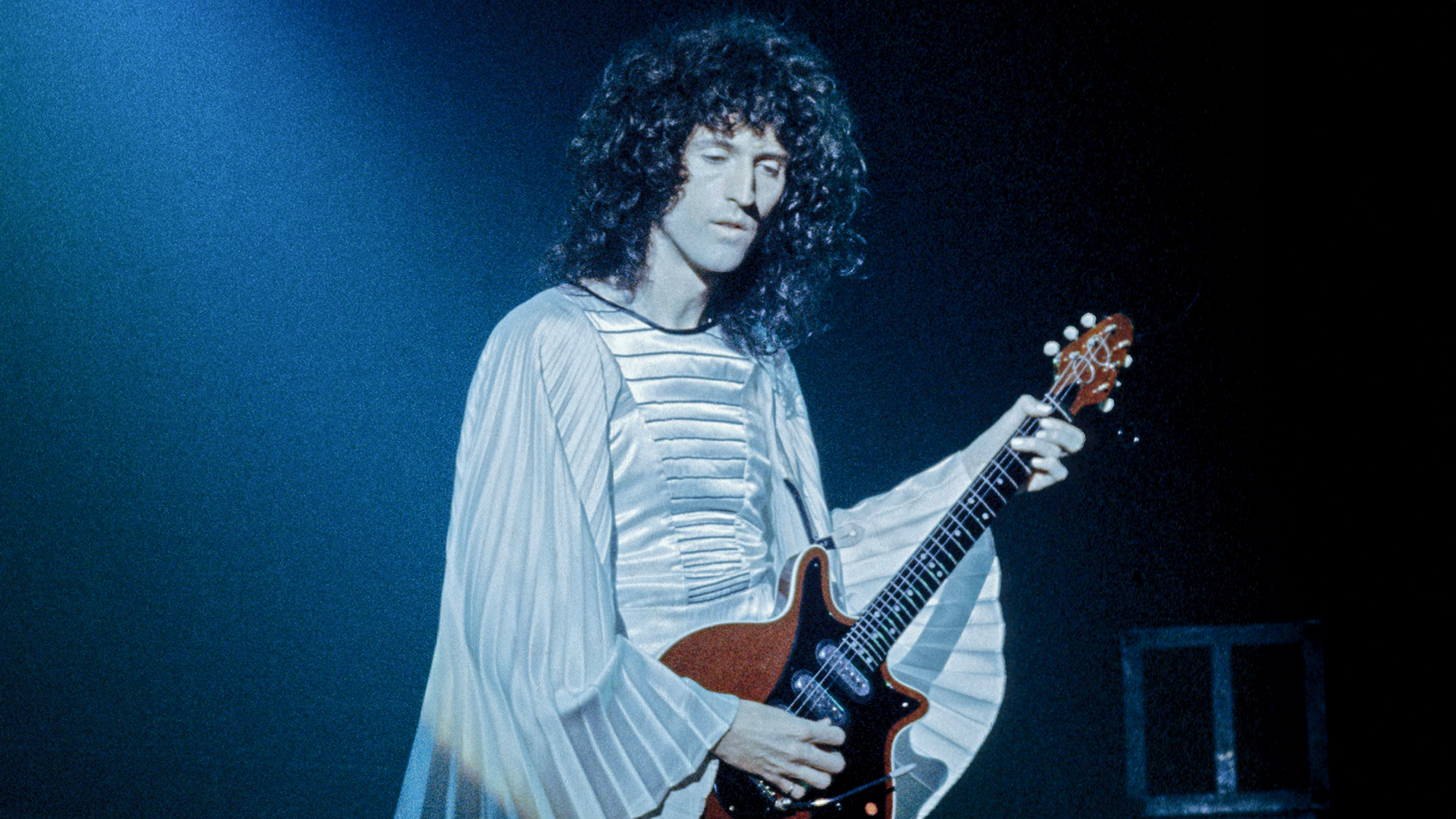 Brian May performing on stage with Queen, February 1975