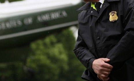 A uniformed Secret Service agent stands his post as President Obama departs the White House.