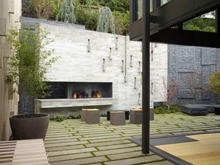paved patio flooring broken up with plants between each stone in a modern urban backyard