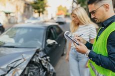 A car insurance adjuster inspects a vehicle after a car accident.