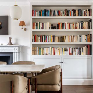 Large bookcase fitted into wall behind dining table