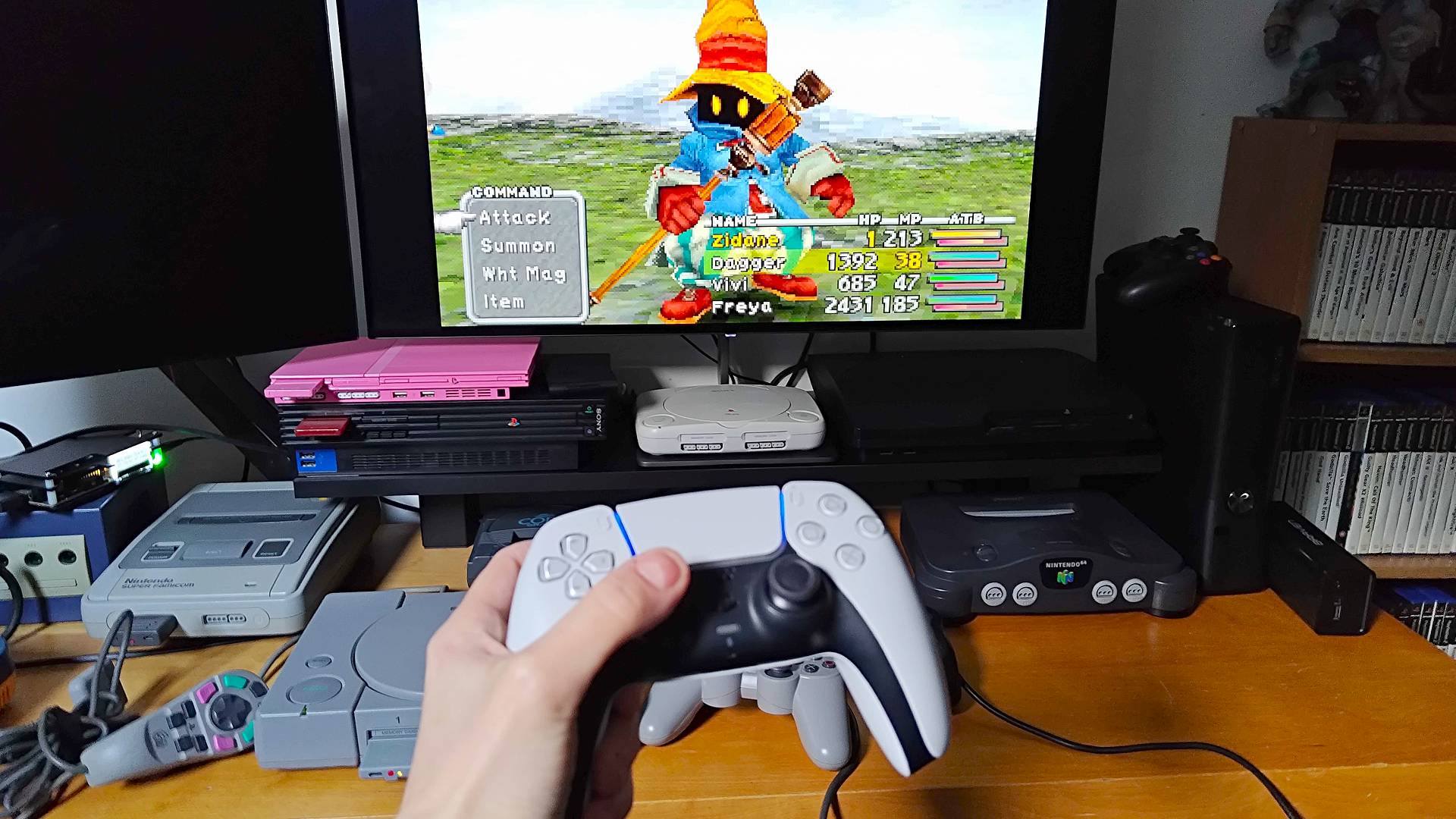 Hand using DualSense synced to PS1 using 8Bitdo Retro Receiver to play Final Fantasy 9 with image of Vivi in battle on monitor in backdrop.