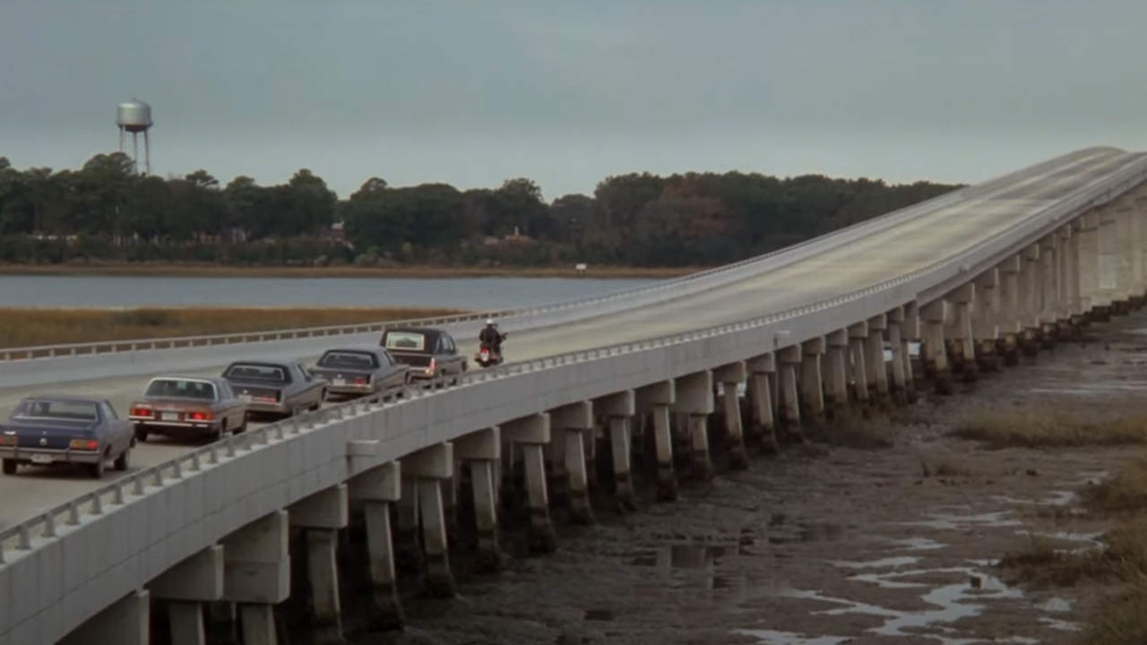 The funeral procession in The Big Chill driving over a long bridge