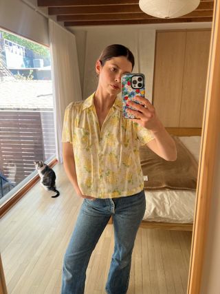 Woman wears a Doen silk top and vintage Levi's jeans.