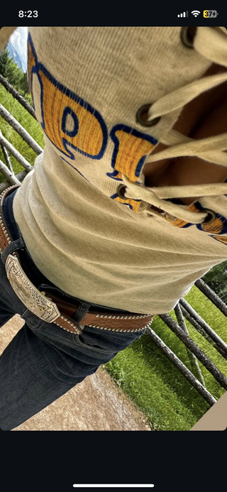 A screenshot of Bella Hadid wearing a pair of bootcut jeans with a large belt and a tank top.