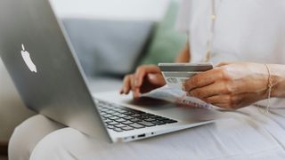 Person Using a Macbook and Holding a Credit Card