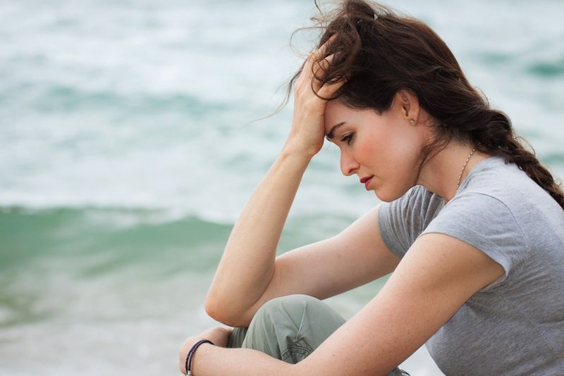 A woman sits, looking depressed