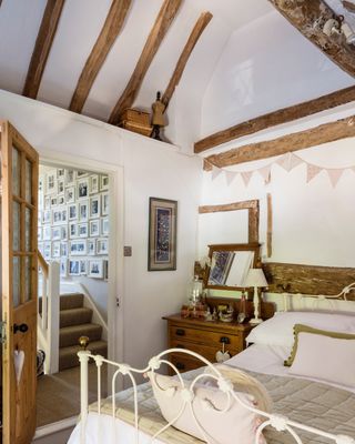 bedroom with original beams and wrought iron bed in a 17th-century cottage