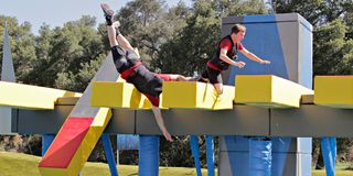Competitors stumble on an obstacle on Wipeout