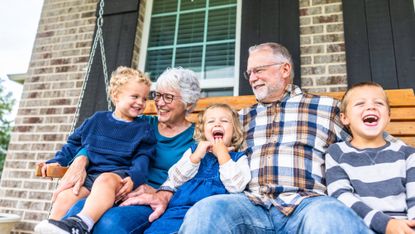 Grandparents and their grandchildren sitting on the home porch swing
