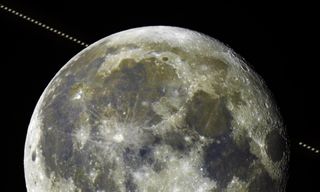 A close-up of the moon with Saturn passing in the background