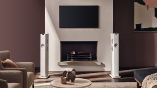 The KEF LS60 standing beside a TV and a fireplace.