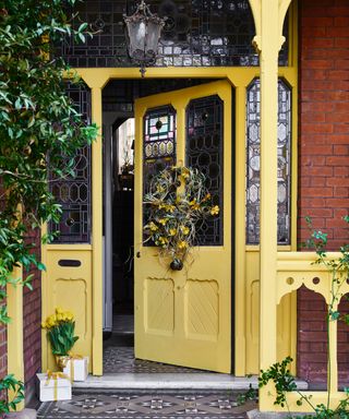 yellow front door porch with spring wreath, traditional lantern, stained glass, patterned tiles