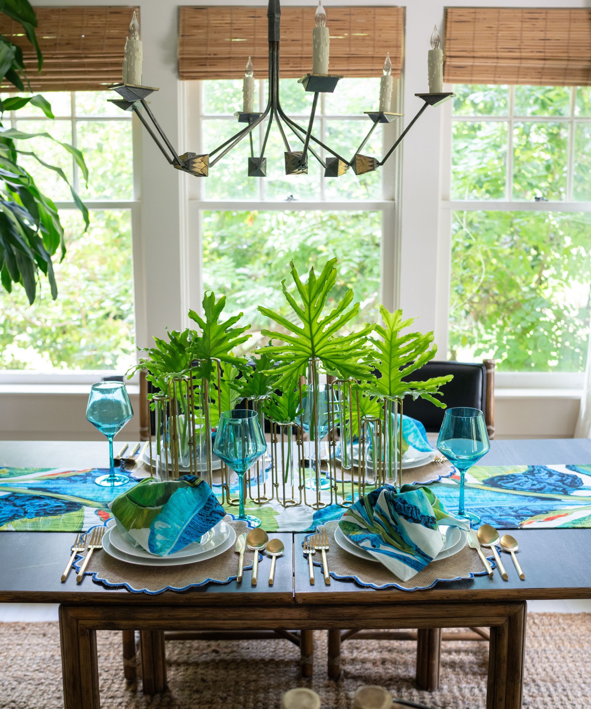 Summer dining table styled with a multi-stem vase filled with tropical leaves