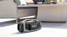 A lifestyle shot of an EGO Power SK1800E Outdoor Speaker on the patio near some garden furniture
