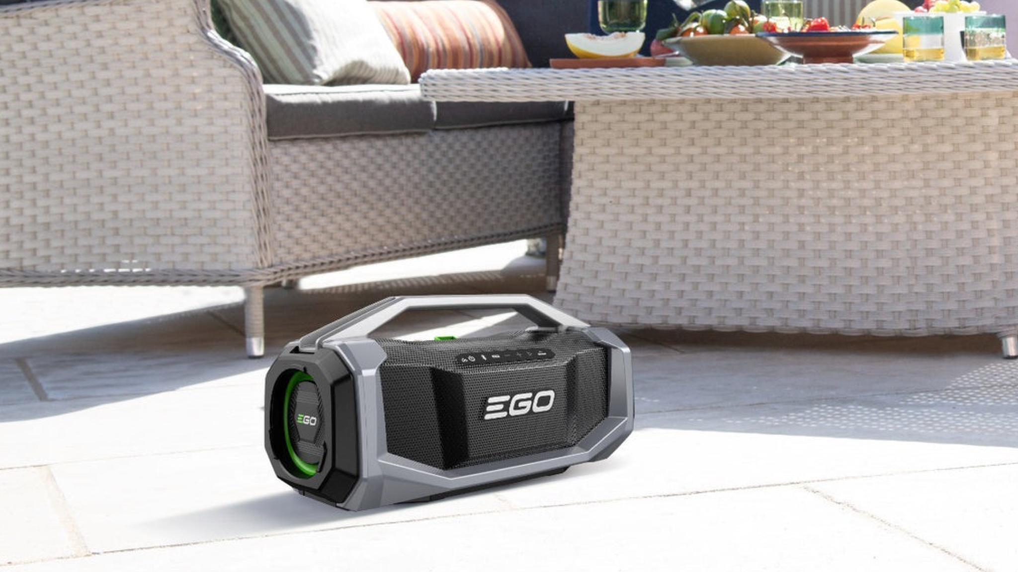 A lifestyle shot of an Ego Power SK1800E Outdoor Speaker on the patio near some garden furniture