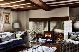 cottage living room with woodburner lit in inglenook and blue chesterfield sofa