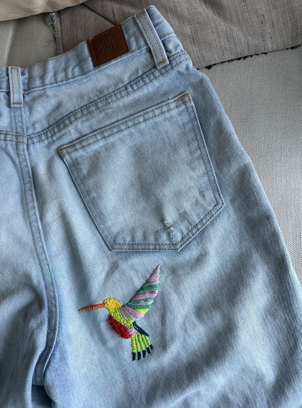 Larissa Mills embroidered blue jeans with a colorful bird