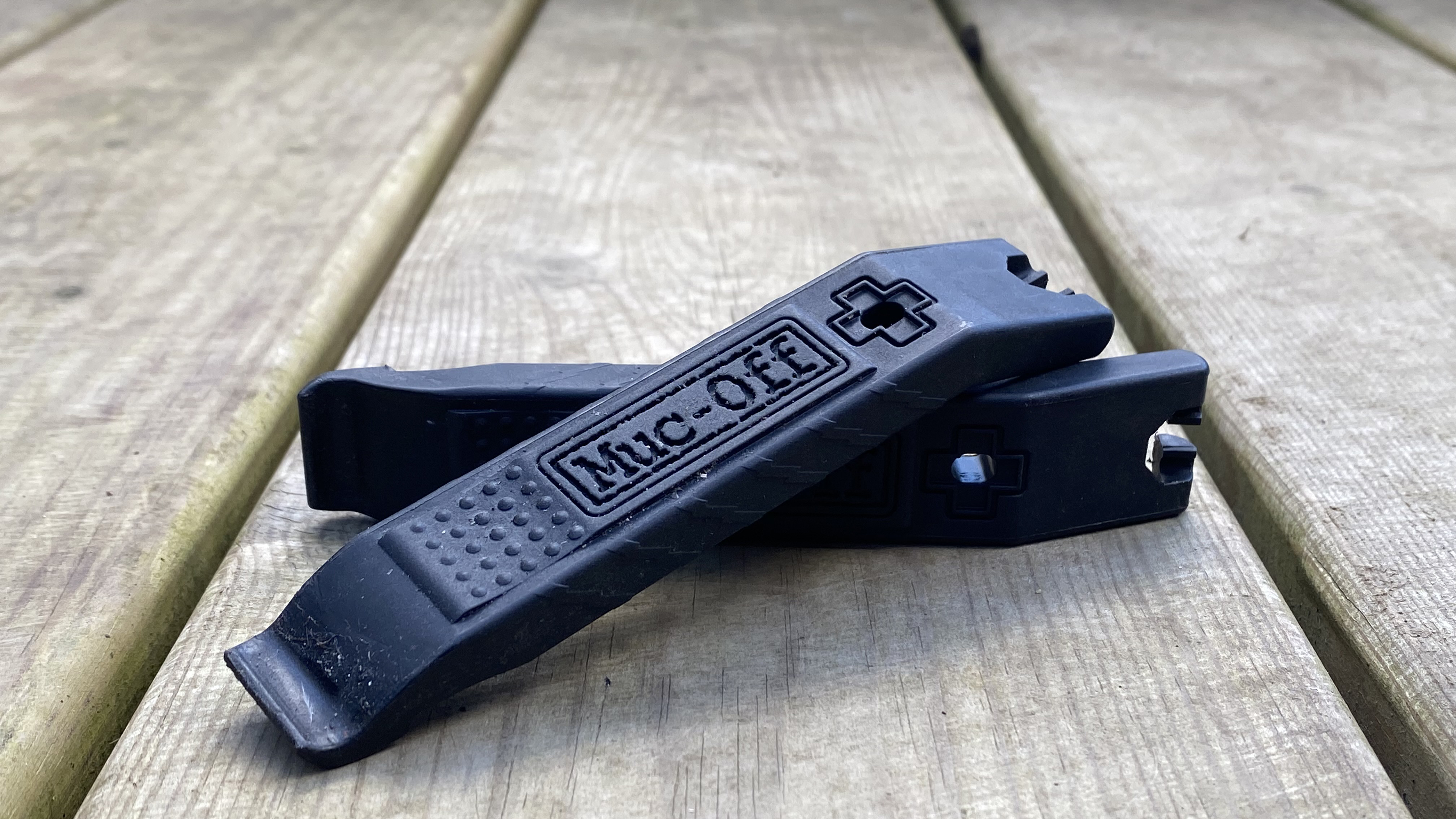 Black Muc-Off Rim Stix tyre levers one resting on top of the other against the backdrop of a wooden deck